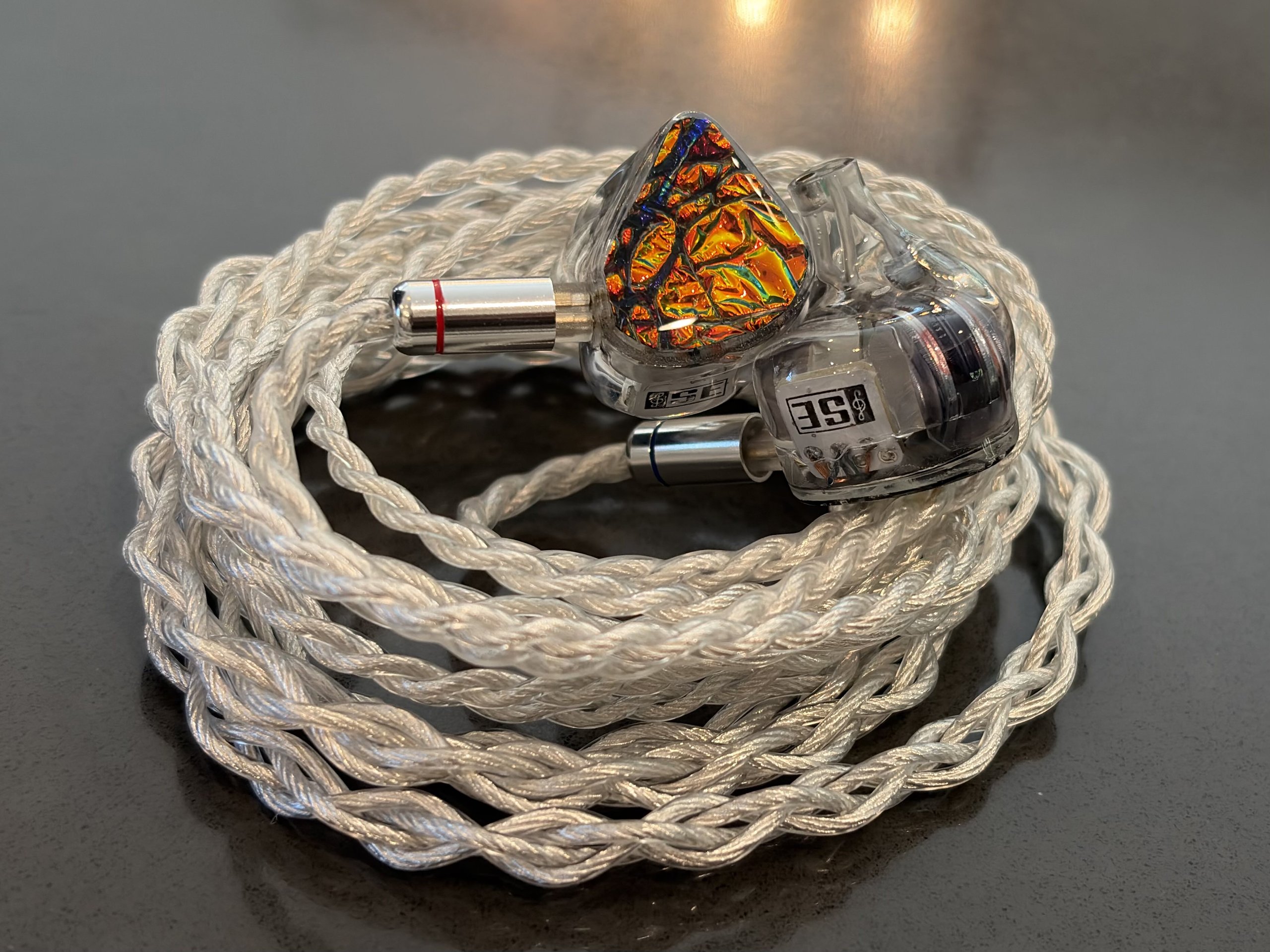 Hexad II IEMs with dichroic fire faceplates on their braided silver cable